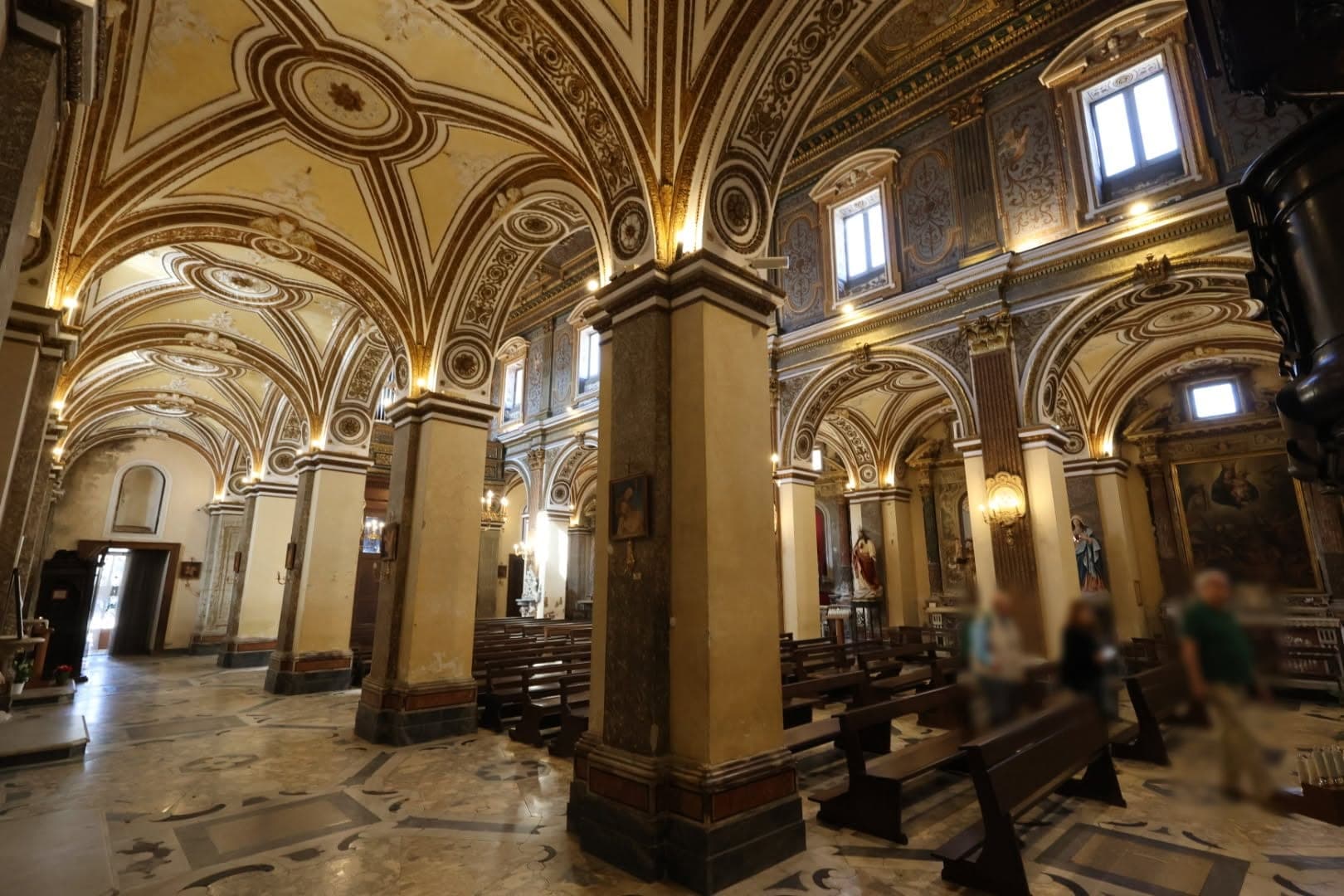 Una navata laterale con le volte decorate a stucco e il pavimento in marmo