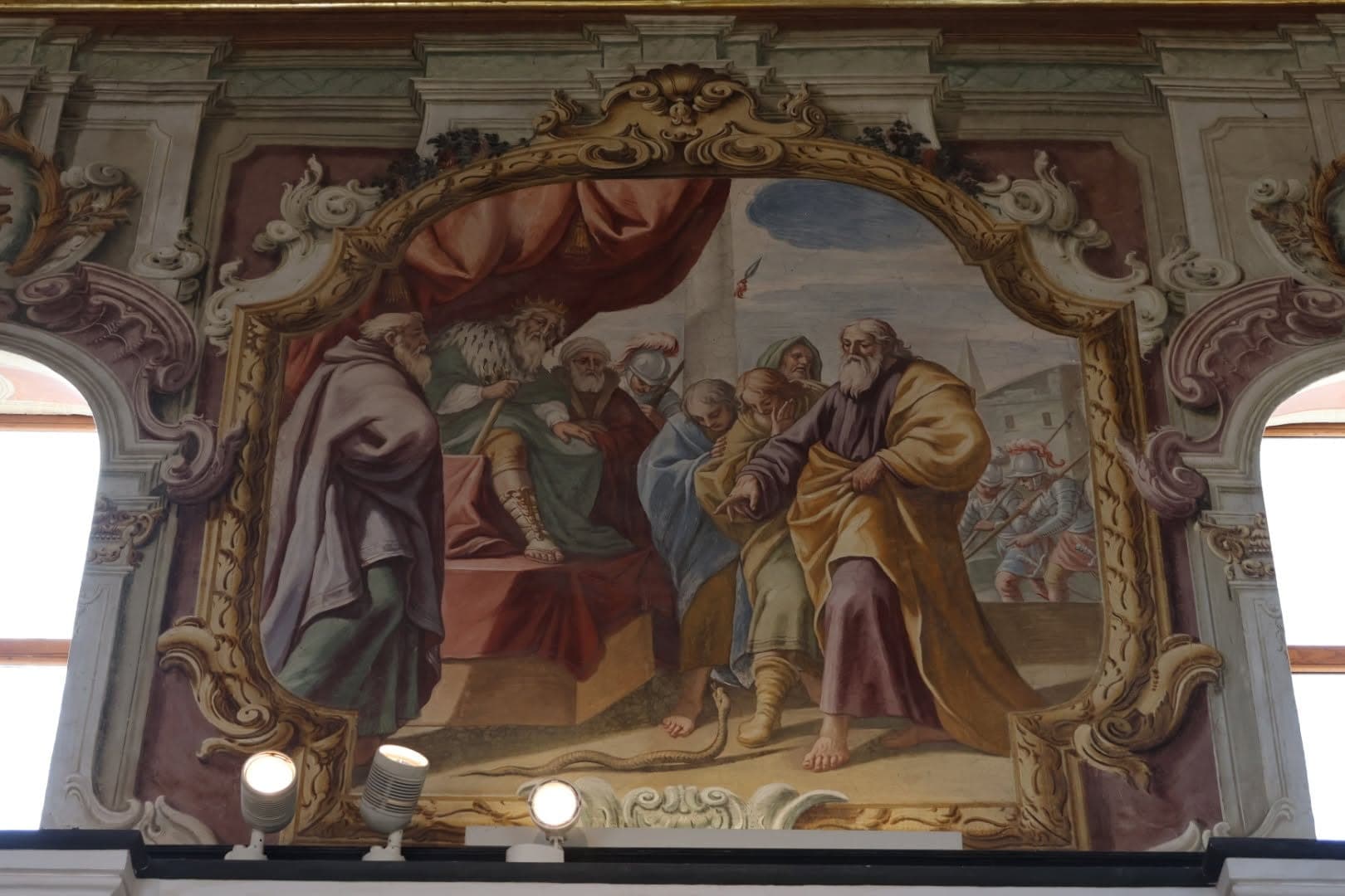 Una delle scene affrescate tra le finestre, con un personaggio in trono sotto un baldacchino rosso